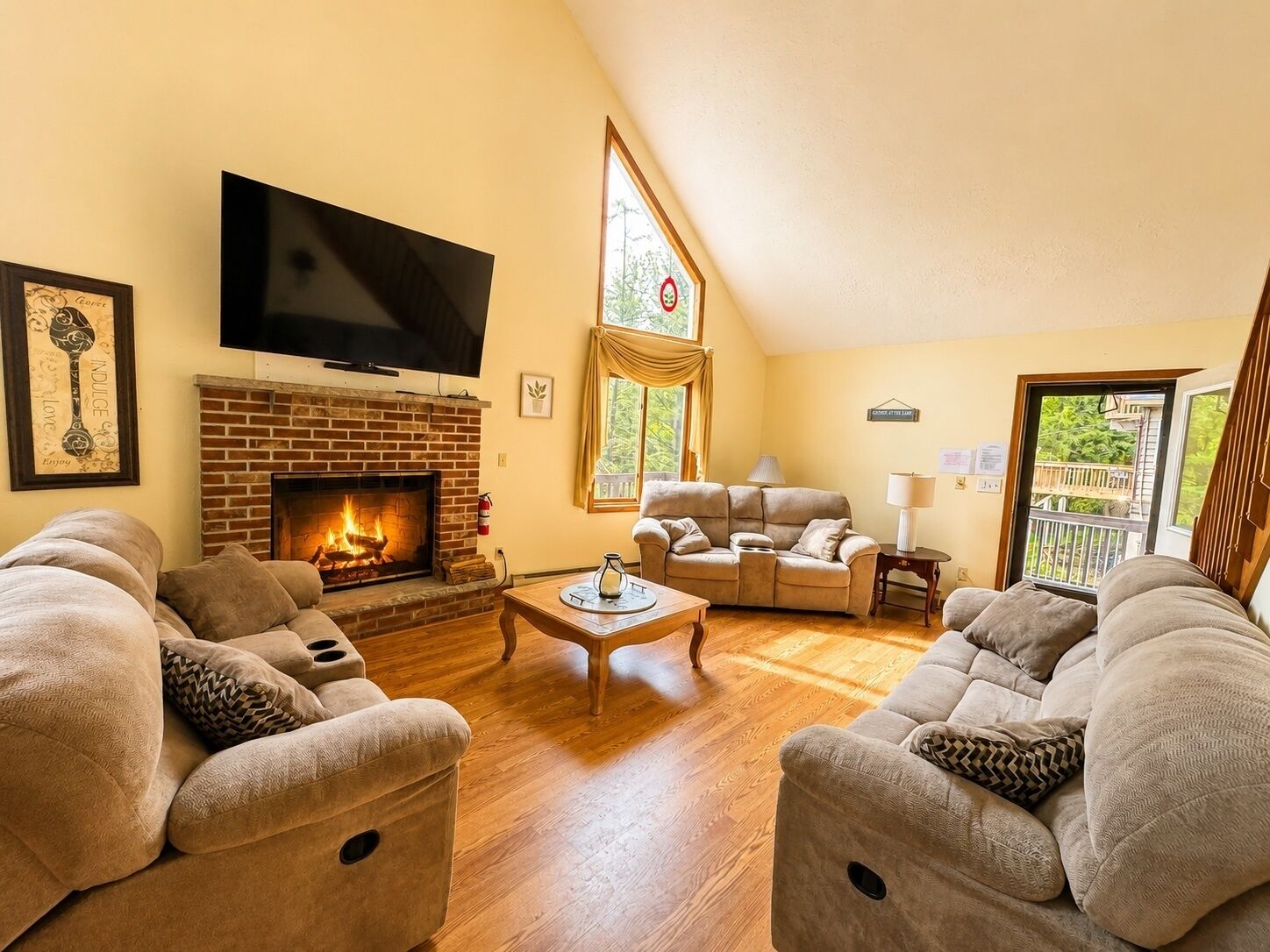 A cozy living room with a fireplace, sofas, a television, and a window with a view.