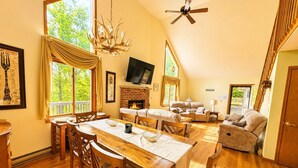 A spacious living area with a fireplace, a dining table with chairs, a sofa, and a television.