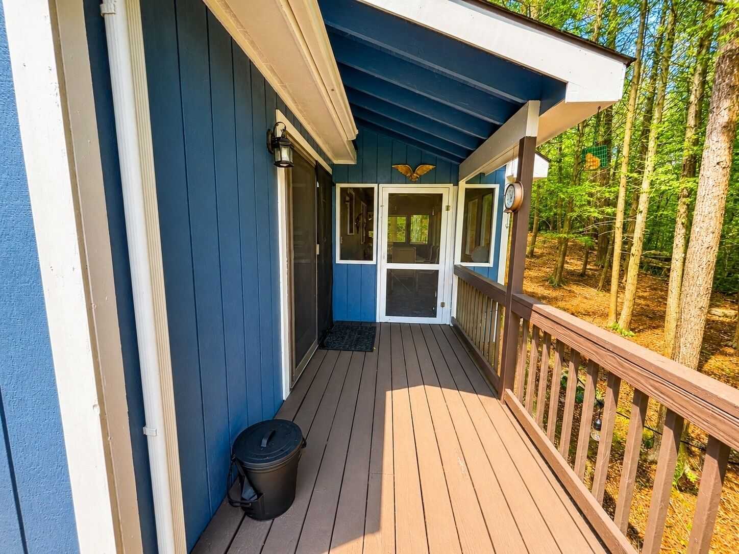A wooden deck with a door leading to a covered porch area.