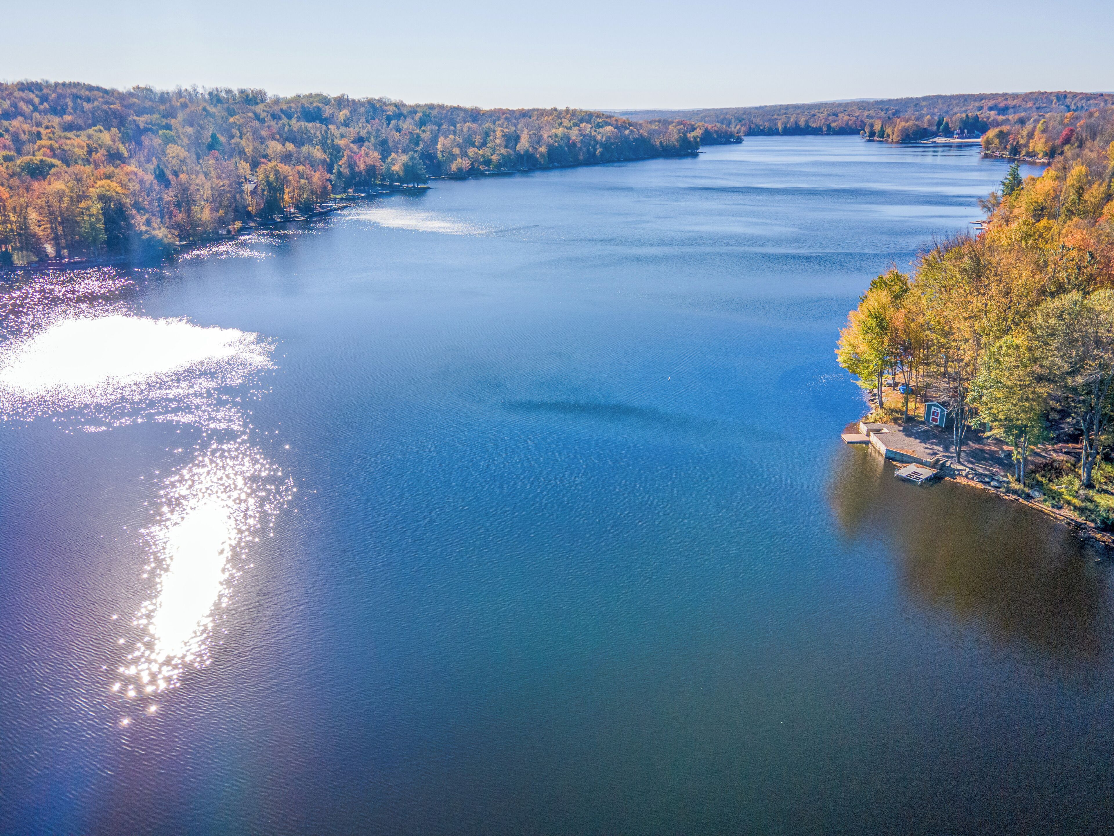 A river with a dock and a small cabin on the right bank.