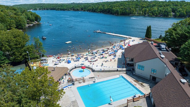 A resort with a swimming pool, beach area, and lake views.