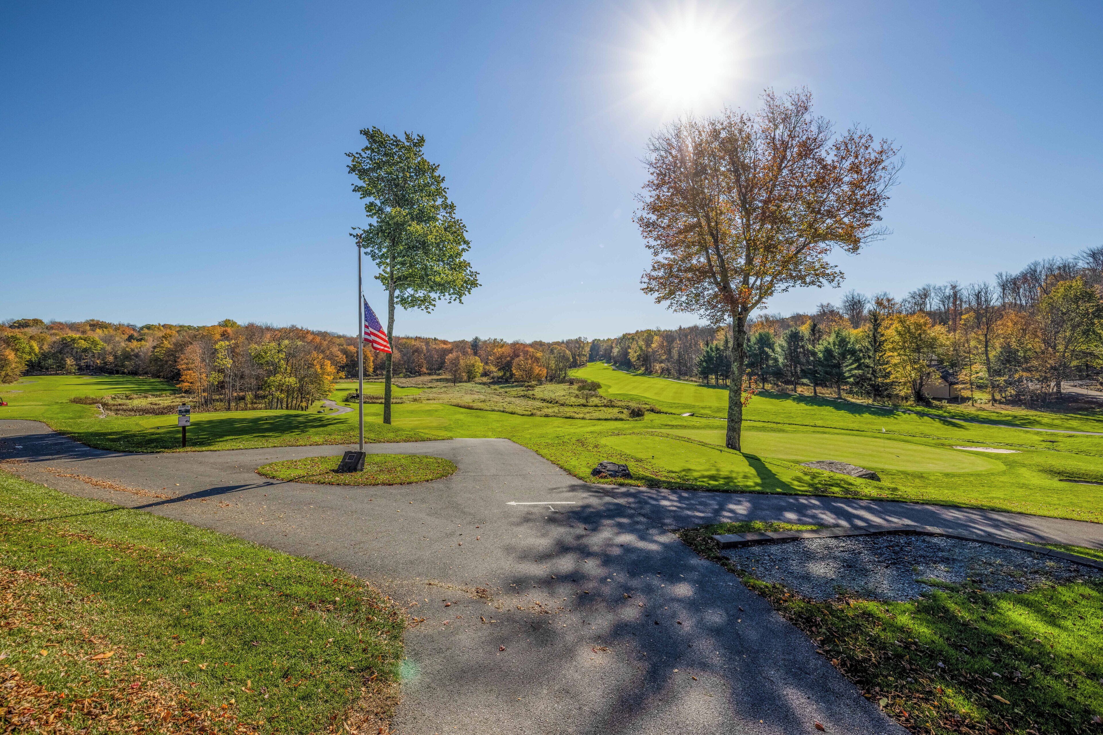 Un terrain de golf avec un mât de drapeau, un drapeau et un ciel dégagé.
