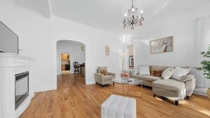 Un salon moderne avec une cheminée, un ensemble de canapés, une table basse et un lustre.
