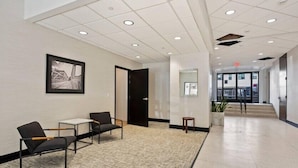 A modern lobby with a carpeted floor, a reception desk, and a framed artwork on the wall. - Town St Medical Lofts (Columbus)