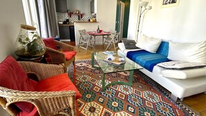 A living room with a glass coffee table, wicker chairs, a white sofa, and a patterned rug. - L'appartement Jean Moulin  (Paris)