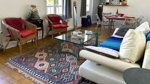 A living room with a sofa, two red chairs, a glass coffee table, and a patterned rug. - L'appartement Jean Moulin  (Paris)