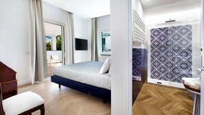 A modern bedroom with a large bed, a wooden chair, and a view of the outdoors through a glass door. - Luxury Villa with Private SPA, Heated Jacuzzi, Pool and Sea-View Terrace (Sorrento)