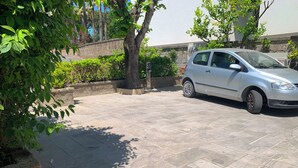 A paved parking area with a car parked, surrounded by greenery and a stone wall. - Luxury Villa with Private SPA, Heated Jacuzzi, Pool and Sea-View Terrace (Sorrento)