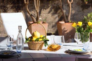 A table set outdoors with a basket of lemons, a bottle of olive oil, and wine glasses. - Luxury Villa with Private SPA, Heated Jacuzzi, Pool and Sea-View Terrace (Sorrento)