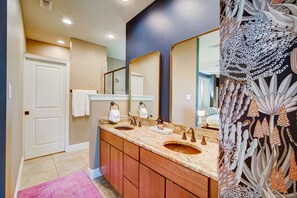 A bathroom with two sinks, a mirror, and a door.