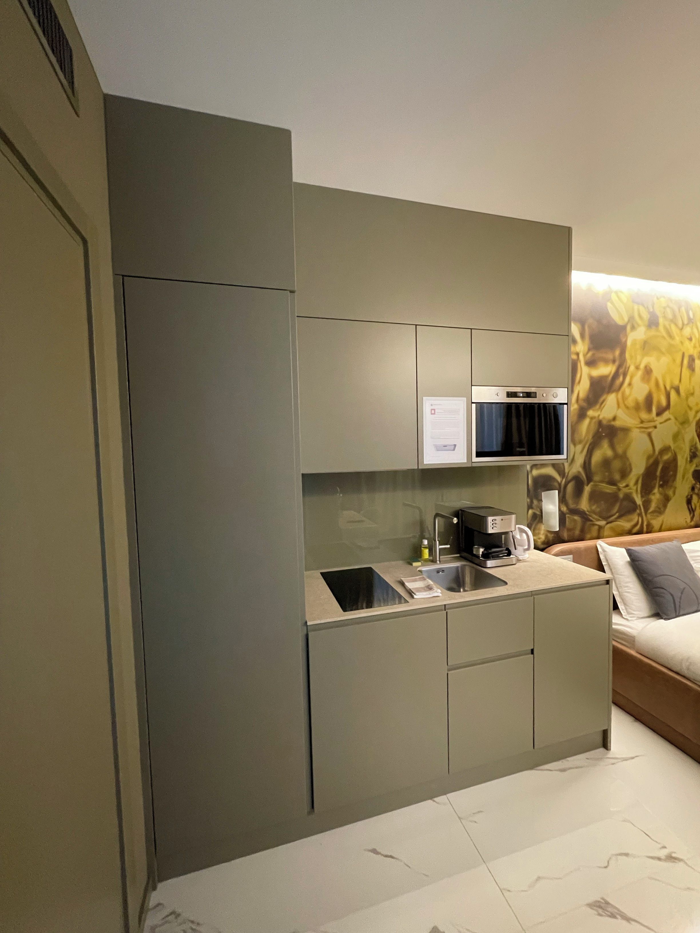 A compact kitchenette with a built-in oven, a coffee maker, and a small sink.