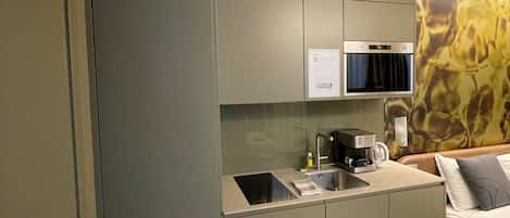 A compact kitchenette with a built-in oven, a coffee maker, and a small sink.