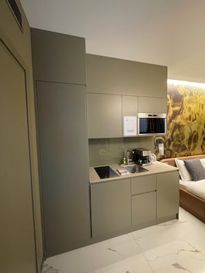 A compact kitchenette with a built-in oven, a coffee maker, and a small sink. - VISIONAPARTMENTS Lugano (Lugano)