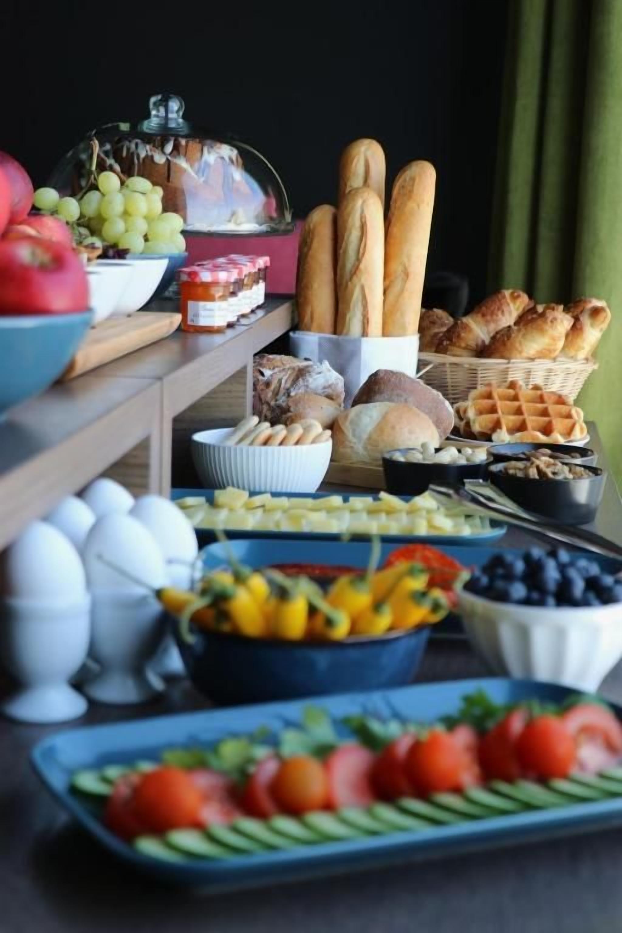 Une table de buffet proposant divers aliments, notamment du pain, des fruits et des légumes.