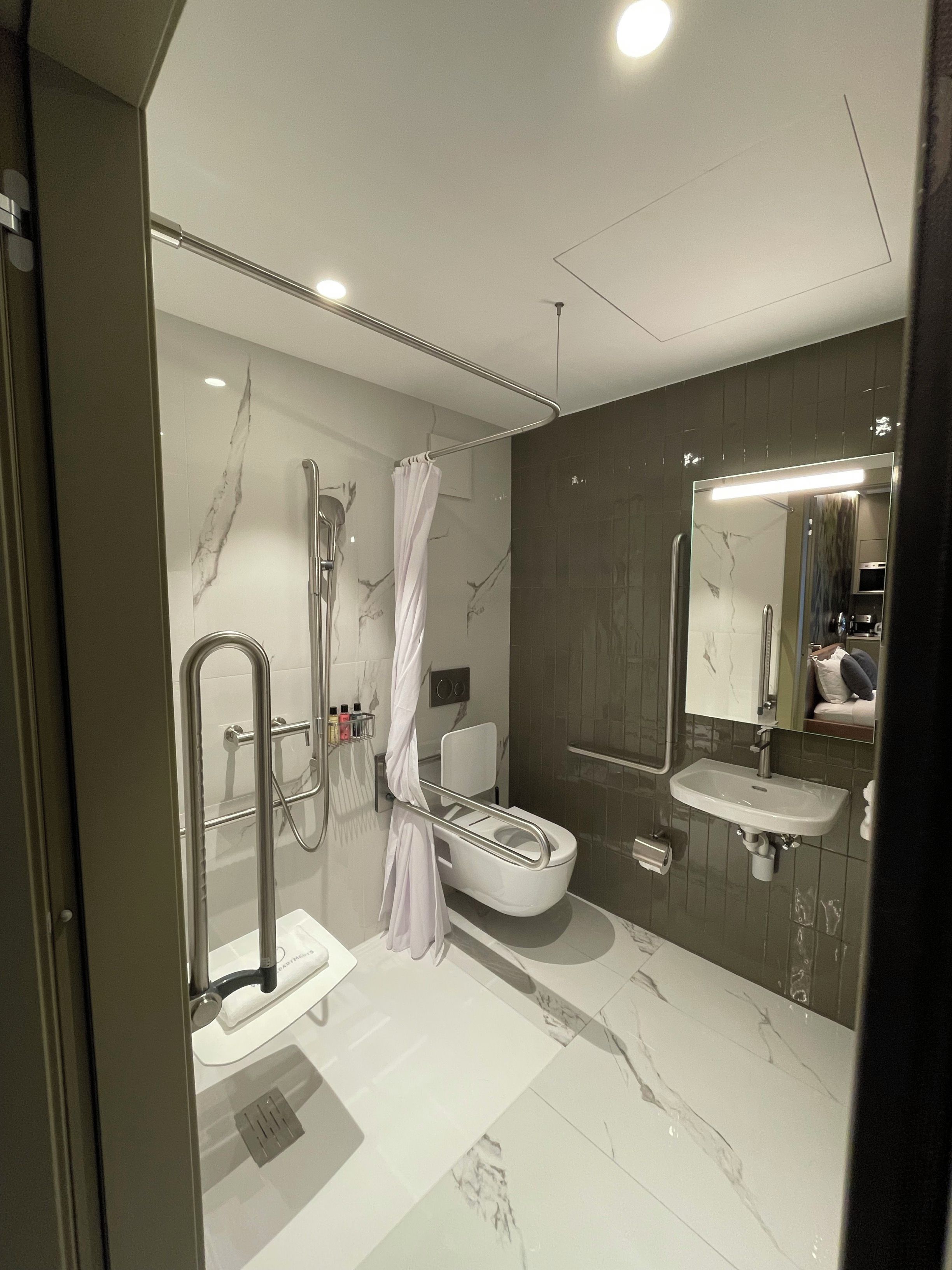 A modern bathroom with a shower, toilet, and sink.