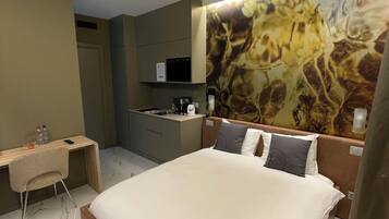 Una habitación de hotel con una cama, un escritorio, un microondas y un cuadro en la pared.