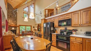 A spacious kitchen with wooden cabinets, a large island, and modern appliances. - Rustic-Meets-Modern Cabin Near Deep Creek (McHenry)