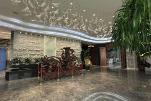 Un hall con piso de mármol, una fuente decorativa y una pared con texto vertical.