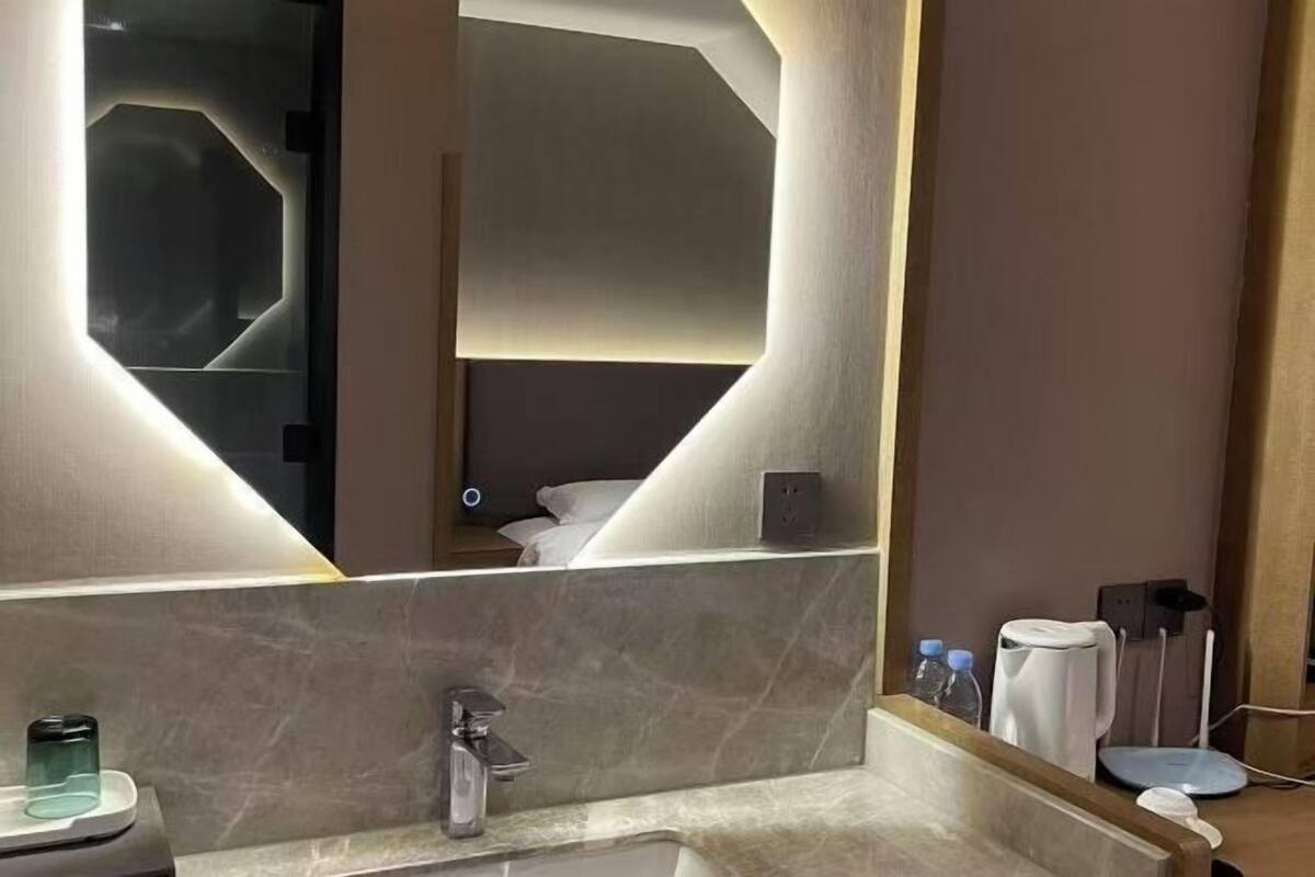 Un baño moderno con un espejo grande, un lavabo y un perchero para toallas.