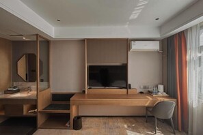 A hotel room with a wooden desk, a mirror, a wardrobe, and a window with curtains. - Zhuoya Smart Hotel (Tonghua)