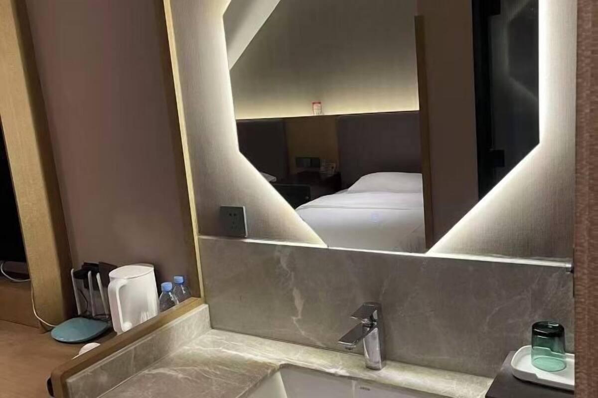 Una habitación de hotel con un espejo grande, un lavamanos y una cama.