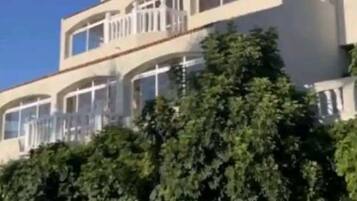 Un immeuble à plusieurs étages doté de balcons, entouré de verdure.