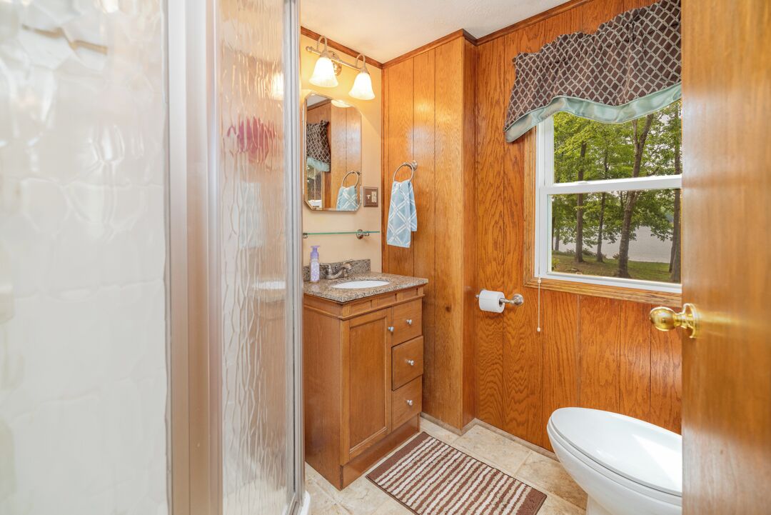 Un baño de madera con inodoro, lavabo y espejo.