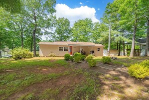 A single-story house with a front porch, surrounded by trees and a well-maintained lawn.