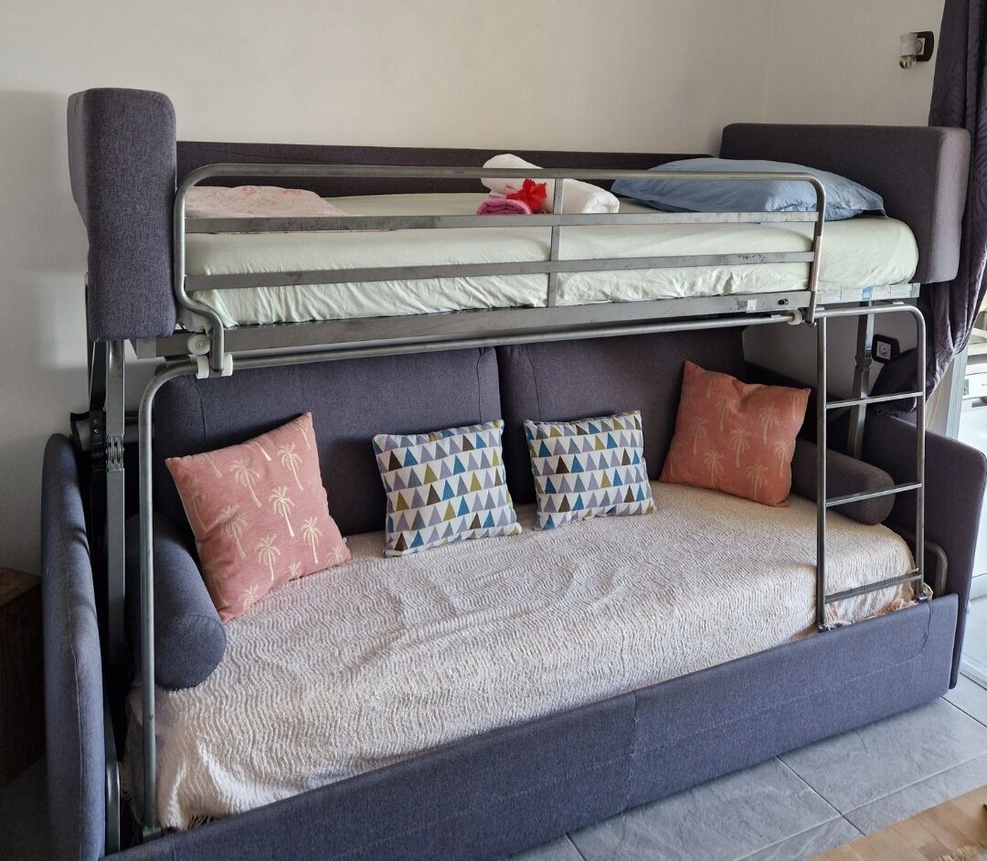 Uma cama de beliche com uma cama inferior, duas almofadas e um cobertor.