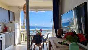 A kitchen with a view of the sea, a dining area with chairs, and a table with a vase of flowers. - Studio Tout Équipé Avec vue mer Dans une Résidence Avec Resto, Piscine, Toboggan (Le Diamant)