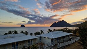 A coastal hotel with multiple buildings, a view of the sea, and a mountain in the background. - Studio Tout Équipé Avec vue mer Dans une Résidence Avec Resto, Piscine, Toboggan (Le Diamant)