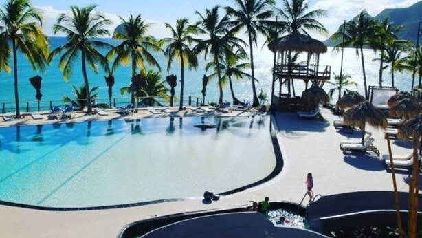 A poolside area with lounge chairs and palm trees, overlooking a body of water. - Studio Tout Équipé Avec vue mer Dans une Résidence Avec Resto, Piscine, Toboggan (Le Diamant)