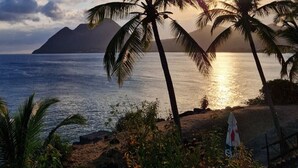A beach scene with palm trees and a mountain in the background. - Studio Tout Équipé Avec vue mer Dans une Résidence Avec Resto, Piscine, Toboggan (Le Diamant)