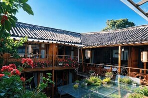A traditional wooden building with a tiled roof, a glass table, and potted plants. - Lijiang Wuge Inn (Lijiang)