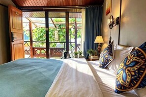 A room with a bed, a nightstand, a lamp, and a view through a window.
