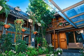 A building with a wooden facade, hanging planters with flowers, and a glass roof. - Lijiang Wuge Inn (Lijiang)
