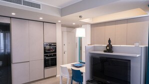 A modern kitchen with built-in appliances, a dining area with a table and chairs, and a TV mounted above the fireplace. - Casa Rattazzi by Wonderful Italy (Albisola Superiore)