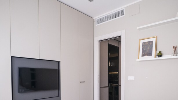 A modern bedroom with a large bed, built-in wardrobe, and a flat-screen TV mounted on the wall. - Casa Rattazzi by Wonderful Italy (Albisola Superiore)
