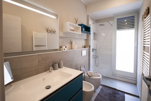 Ein modernes Badezimmer mit einem großen Spiegel, einem Waschbecken, einer Toilette und einer Dusche.