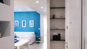 A modern kitchen with white cabinets, a blue accent wall, and a dining area with a white table and sofa. - Casa Rattazzi by Wonderful Italy (Albisola Superiore)