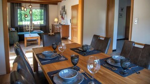 A dining area with a wooden table set for four, surrounded by chairs. - Gemütliche Ferienwohnung in der Vulkaneifel Casa Oos (Rockeskyll)