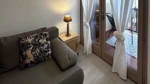Una sala de estar con sofá, lámpara y vistas al exterior a través de un ventanal.