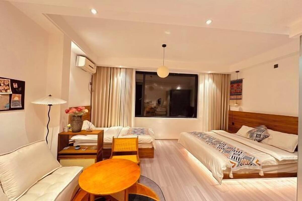 A hotel room with a bed, a sofa, a dining table, and a window.