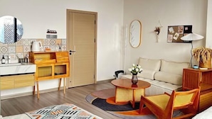 Un salon moderne comprenant un canapé, une table basse et un coin repas avec un buffet en bois et un miroir.