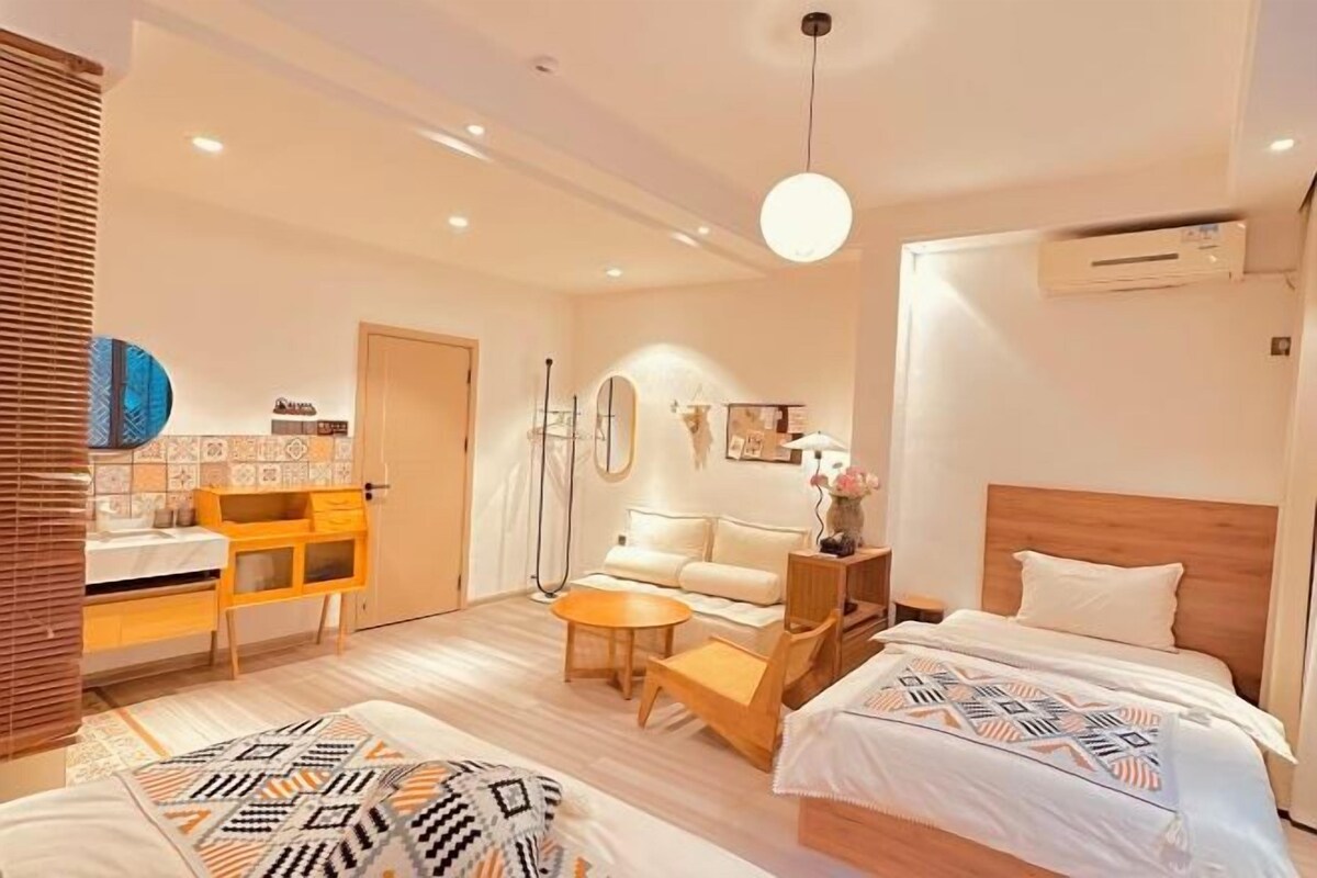 Ett modernt hotellrum med en säng, soffa, skrivbord och en liten matplats.
