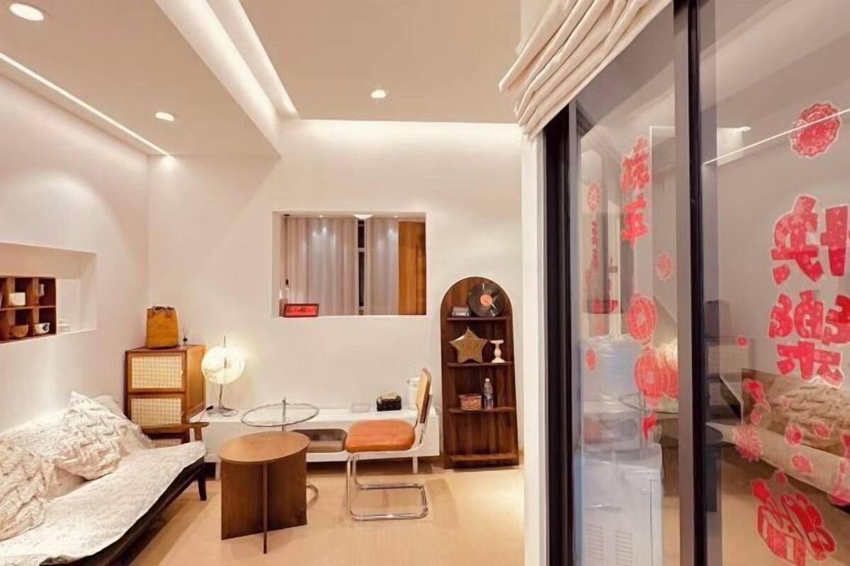A modern room with a bed, a round table, a chair, a lamp, and a window.