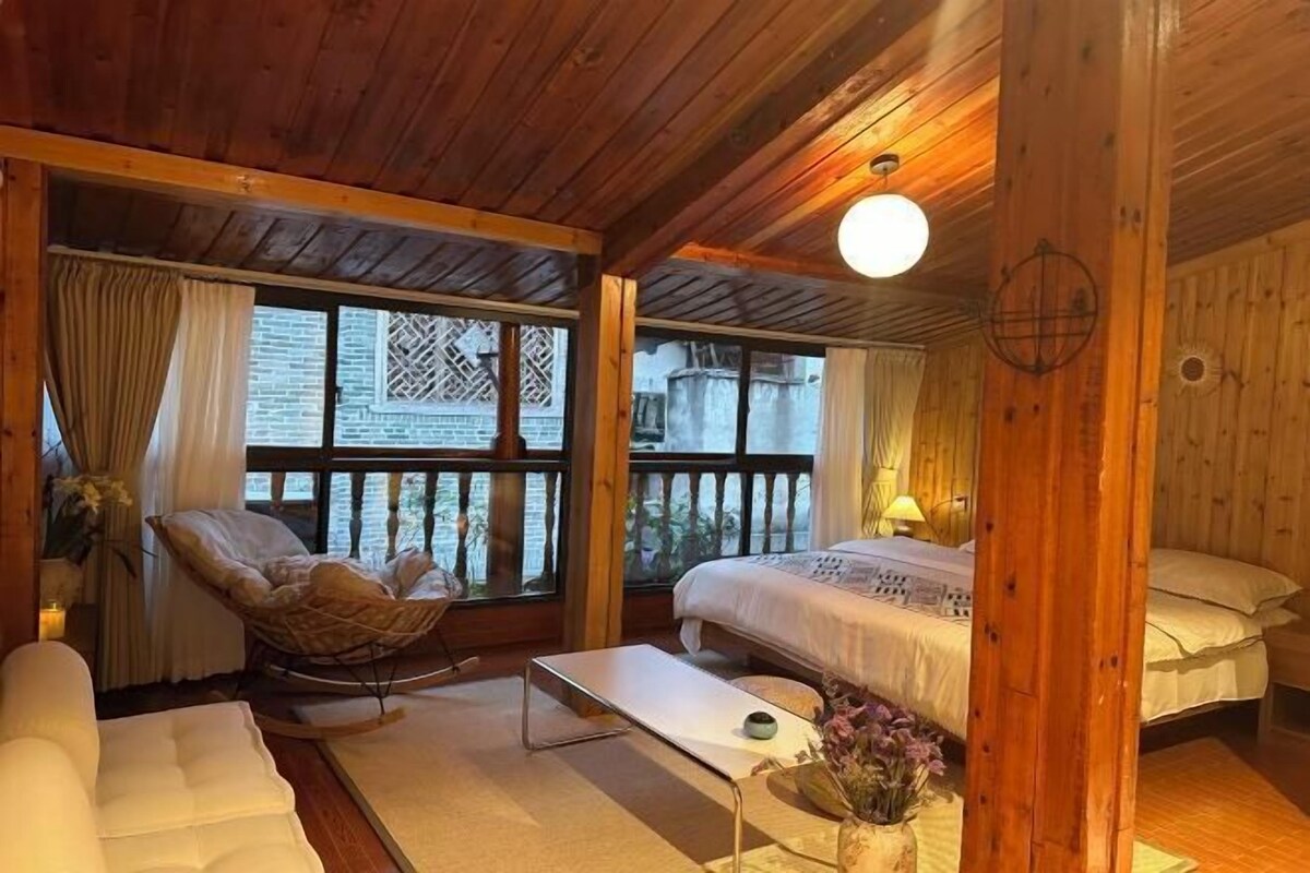 Une pièce chaleureuse, aménagée dans un chalet en bois, avec un lit, une chaise, un canapé et une petite table.