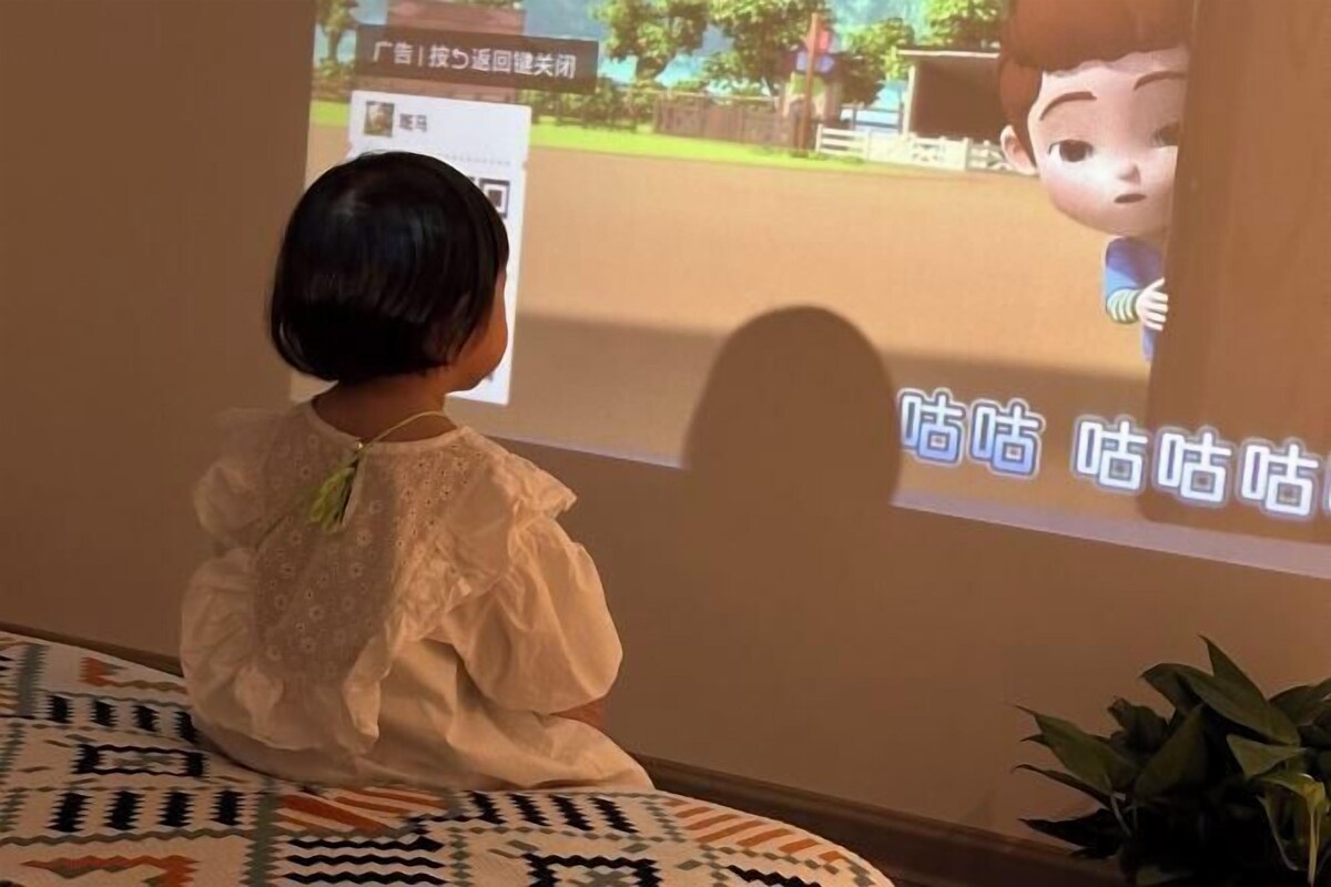 Un enfant qui regarde une image projetée sur un mur.