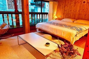 A cozy bedroom with a wooden ceiling, a bed with patterned bedding, a bedside table with a lamp, and a view of the outside through a window. - Wangxiansheng Homestay (Fenghuang Ancient Town) (Fenghuang County)