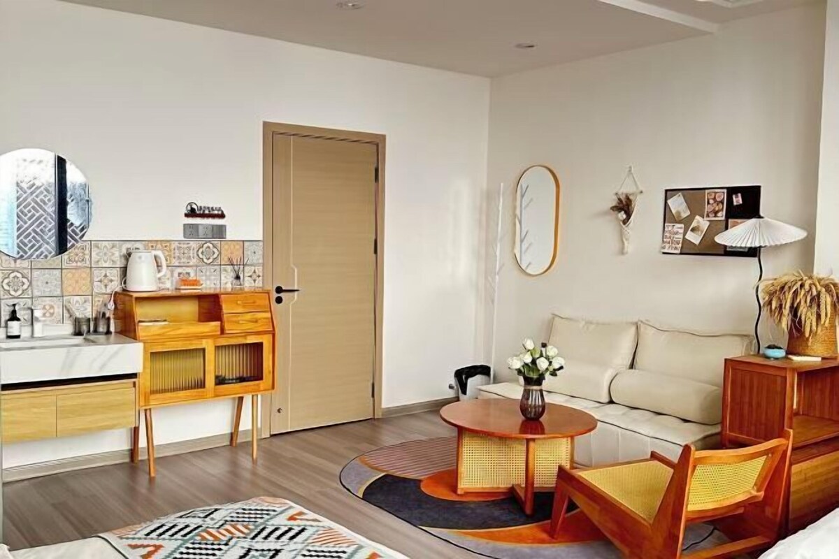 Un salon moderne comprenant un canapé, une table basse et un coin repas avec un buffet en bois et un miroir.